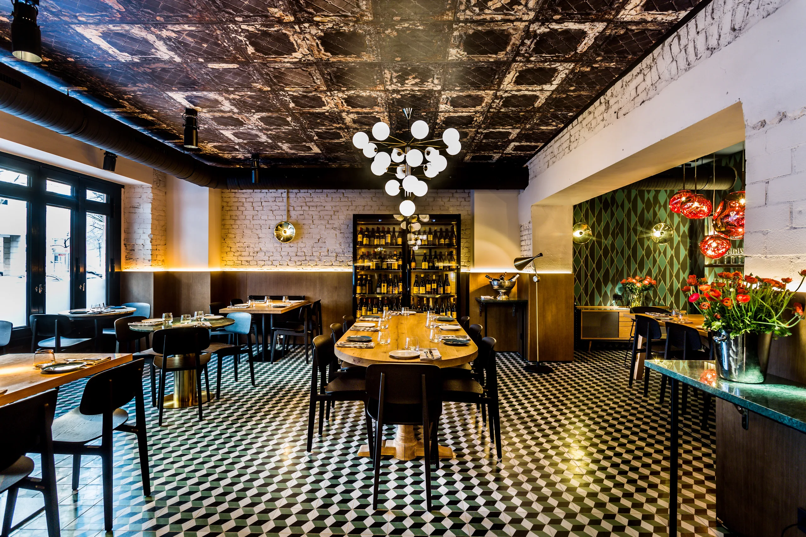 Main dining room set for a full restaurant buyout, with the communal table, wine display shelves and checkerboard floor