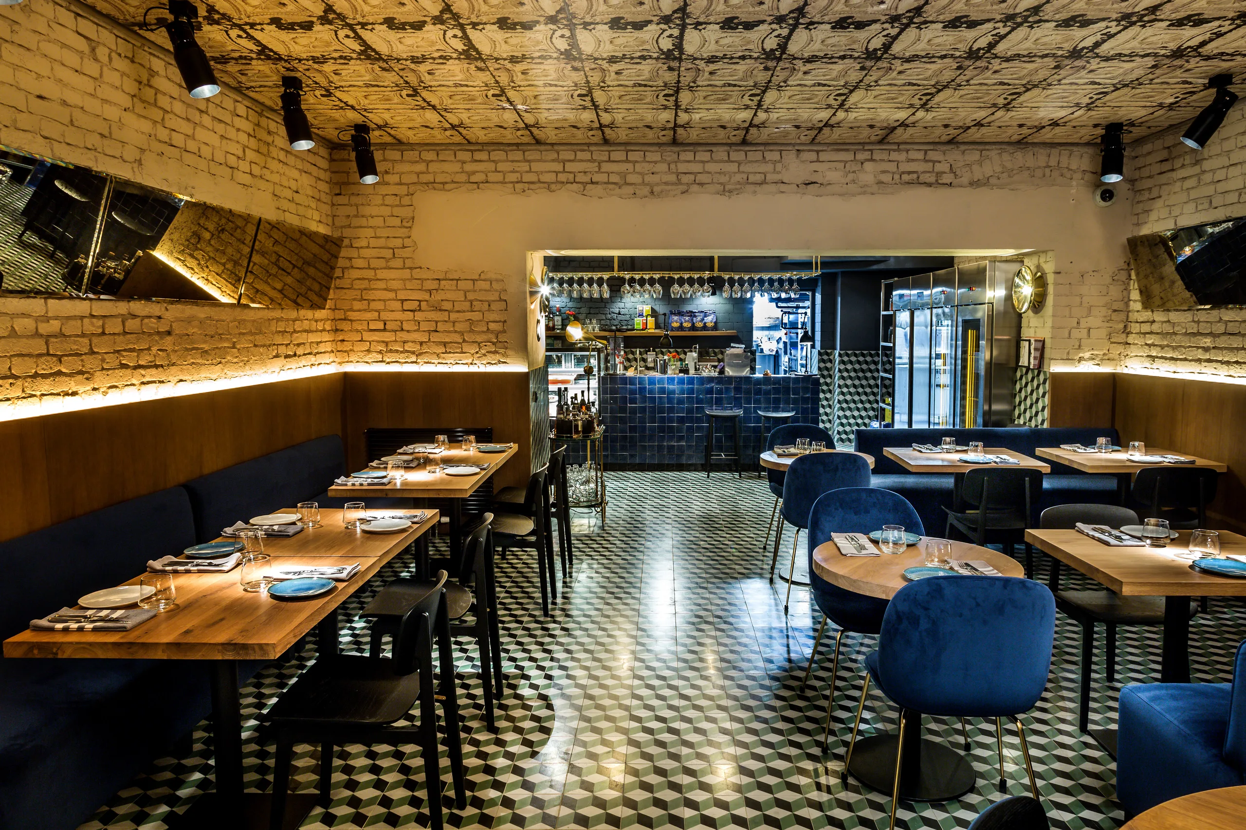 Dining area with blue velvet chairs and booths, looking toward the bar