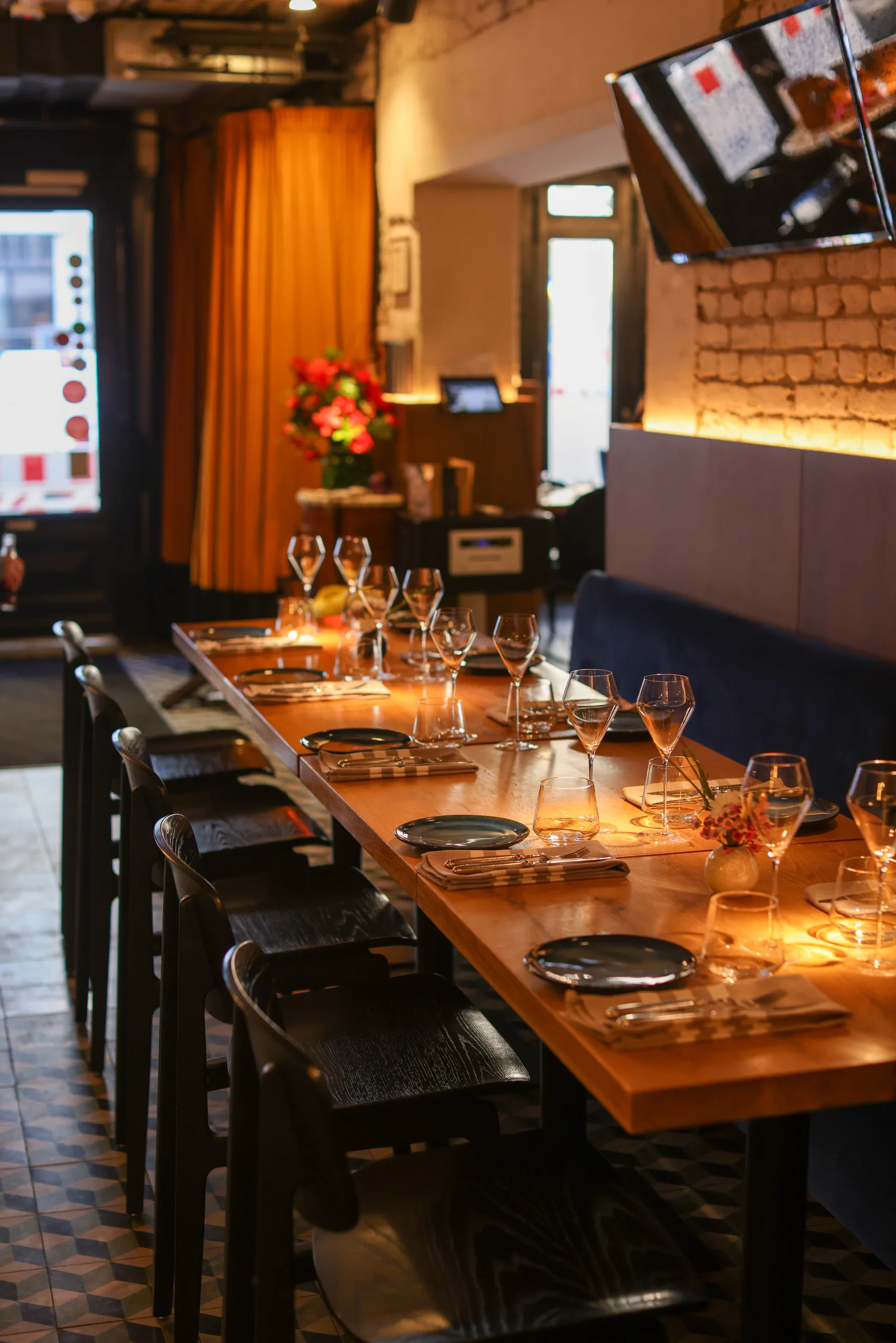 Long communal table set for a group, with wine glasses and place settings along the banquette